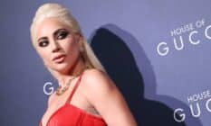 Lady Gaga wears a red dress as she stares over her shoulder at something positioned off camera