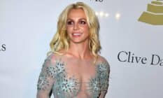 Britney Spears smiles at someone off camera while wearing a semi-transparent dress with blue crystal details on it