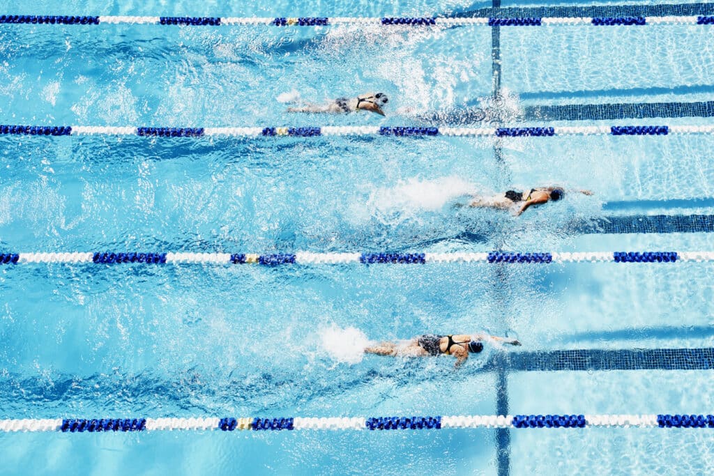 Jeunes nageurs de compétition faisant la course dans la vue aérienne de la piscine extérieure.