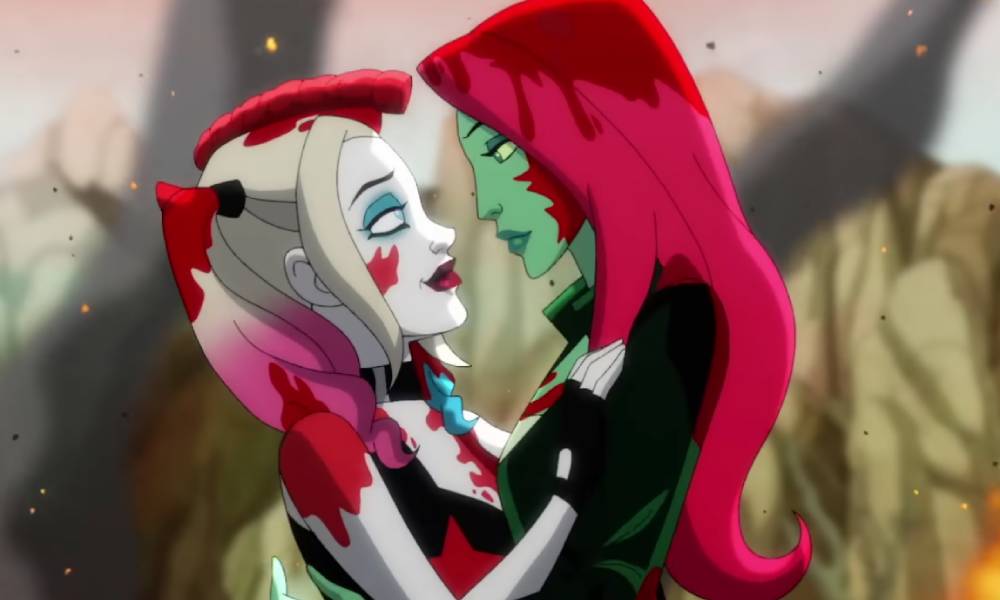 In a still from HBO Max's Harley Quinn series, Harley holds Poison Ivy close as they stare into each other's eyes. Both villain's have blood splatters on their bodies