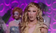 Drag Race Down Under season two queen Faúx Fúr looks off camera while wearing a cream outfit with other queens standing in the background