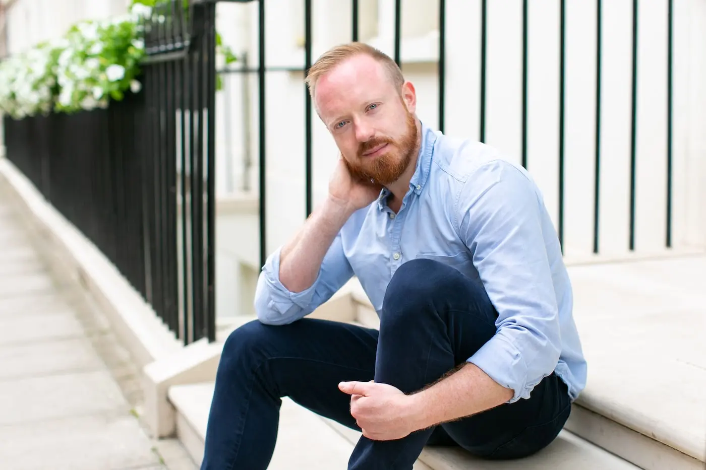 Daniel O'Shaughnessy wearing a blue shirt and jeans pictured sitting on a step.