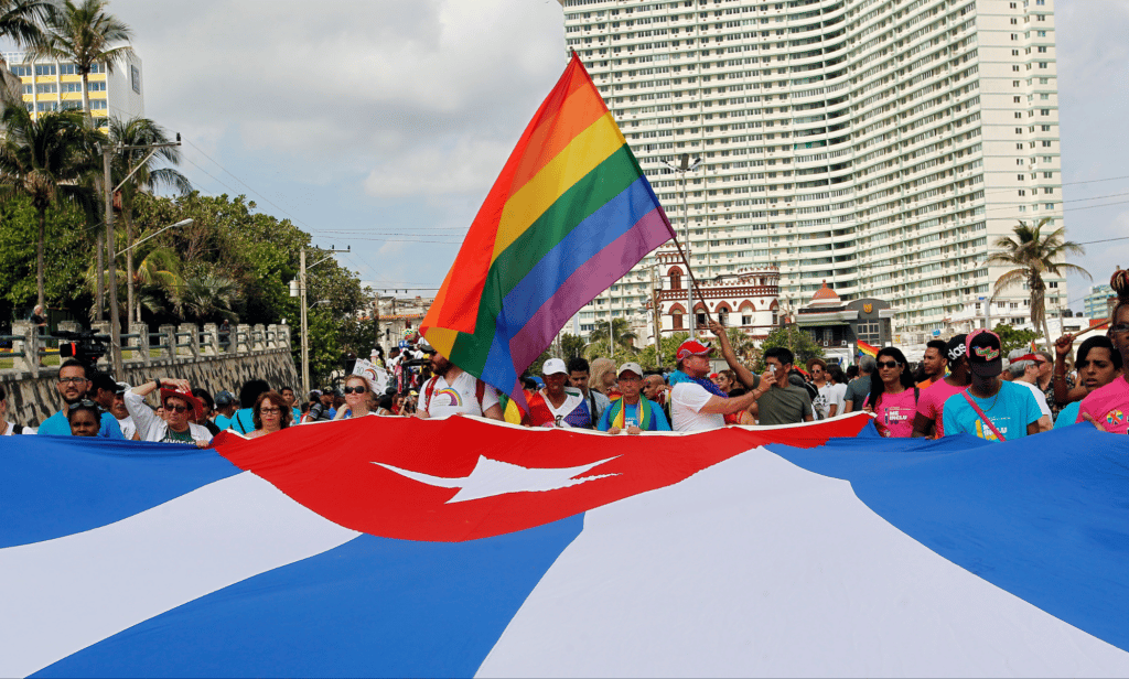 LGBTQ+ advocates hold up a rainbow flag and a Cuban flag