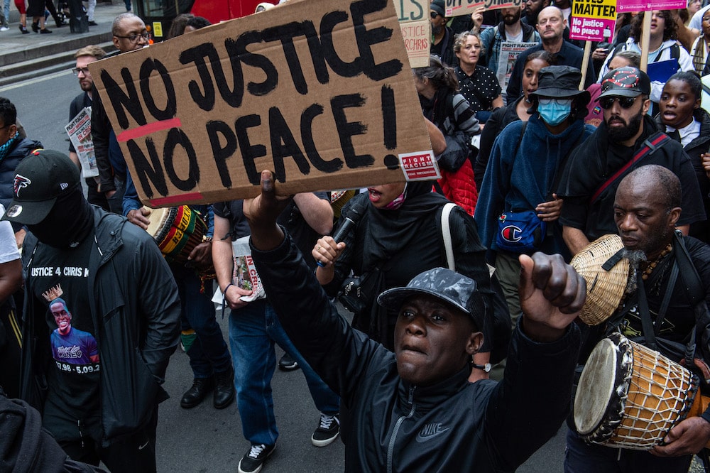 Les manifestants tiennent une pancarte indiquant "sans justice, sans paix" lors d'une marche à Londres