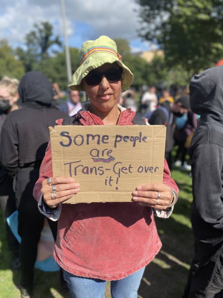 Un manifestant détient une carte de droits trans