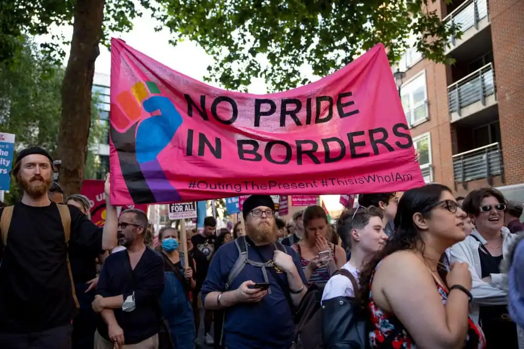 Protesters from the LGBTQ+ group hold a banner during the demonstration at Home Office.